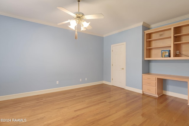 unfurnished office featuring built in desk, ceiling fan, light wood-type flooring, and crown molding