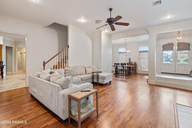 living room with dark wood-type flooring, ceiling fan with notable chandelier, and crown molding