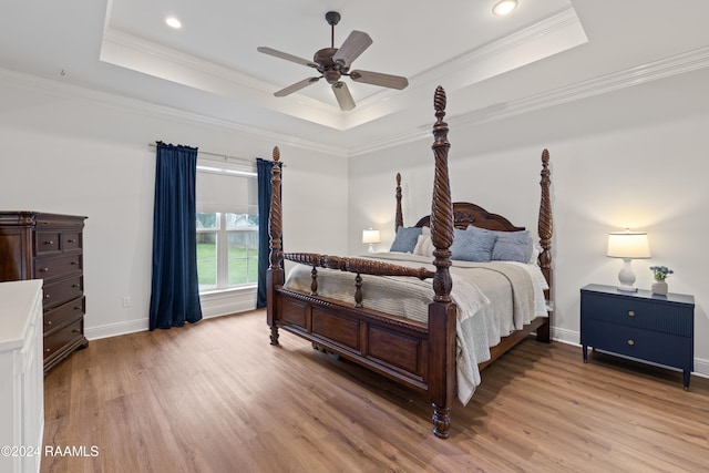 bedroom featuring light wood-type flooring, crown molding, and a tray ceiling