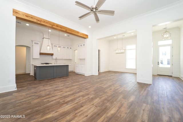 unfurnished living room featuring ornamental molding, arched walkways, a ceiling fan, and dark wood-style floors