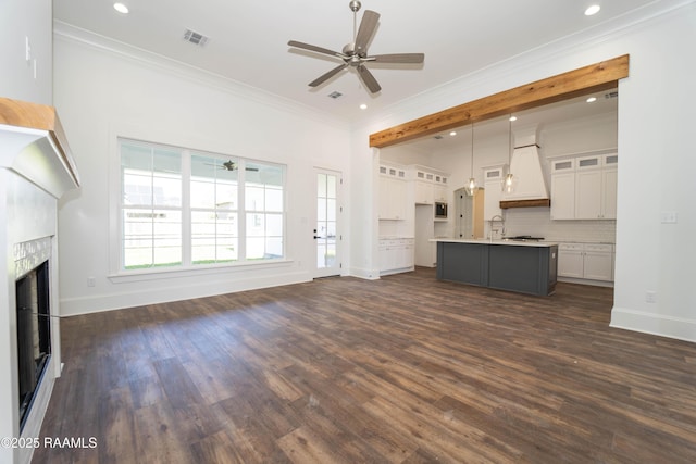 unfurnished living room with dark wood-style floors, visible vents, ornamental molding, and a tile fireplace