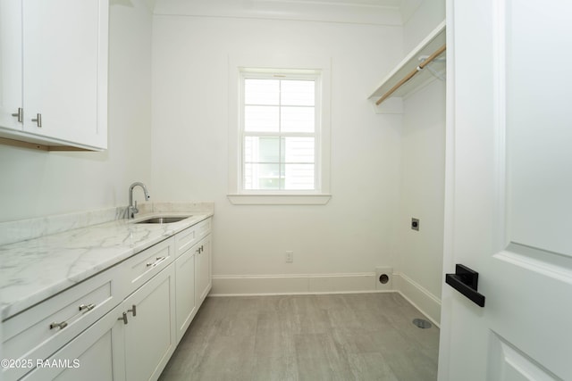 clothes washing area with cabinet space, a sink, electric dryer hookup, and baseboards