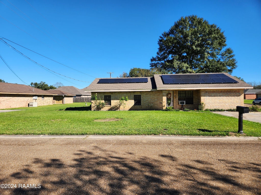 ranch-style home with a front lawn and solar panels