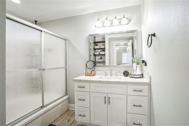 full bathroom featuring wood finished floors, vanity, and a shower with door