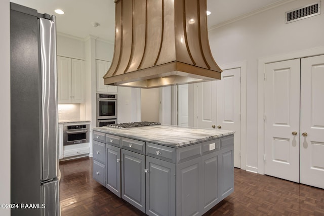 kitchen featuring appliances with stainless steel finishes, custom exhaust hood, crown molding, a center island, and gray cabinets