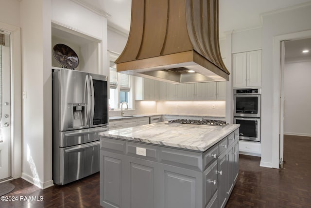 kitchen featuring gray cabinetry, a center island, stainless steel appliances, crown molding, and custom exhaust hood