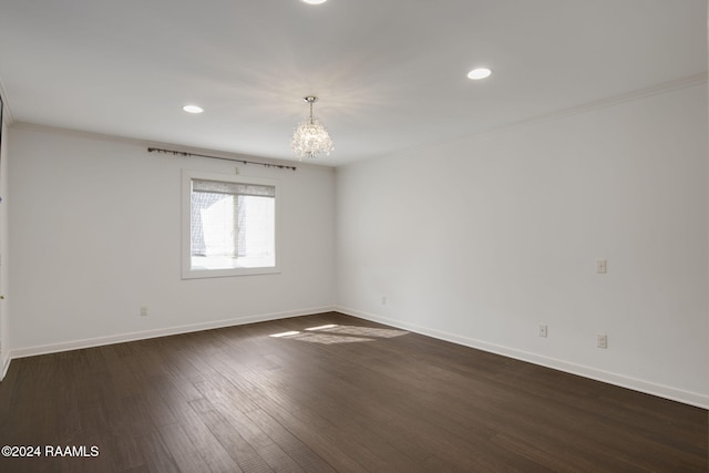 spare room featuring dark hardwood / wood-style flooring, a chandelier, and ornamental molding