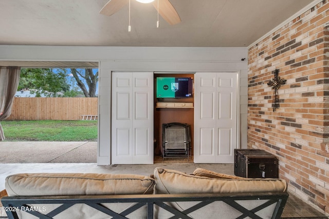 unfurnished living room featuring ceiling fan, crown molding, and brick wall