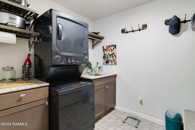 kitchen with sink, stacked washer and clothes dryer, and light tile patterned flooring