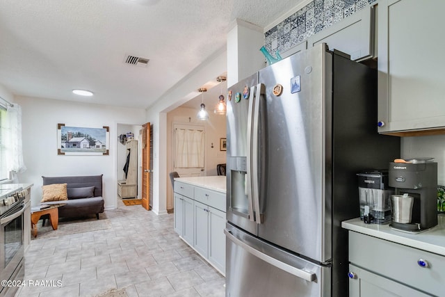 kitchen featuring stainless steel appliances, hanging light fixtures, and a textured ceiling