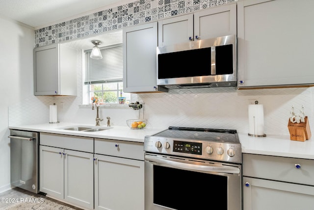 kitchen with tasteful backsplash, gray cabinets, sink, and appliances with stainless steel finishes