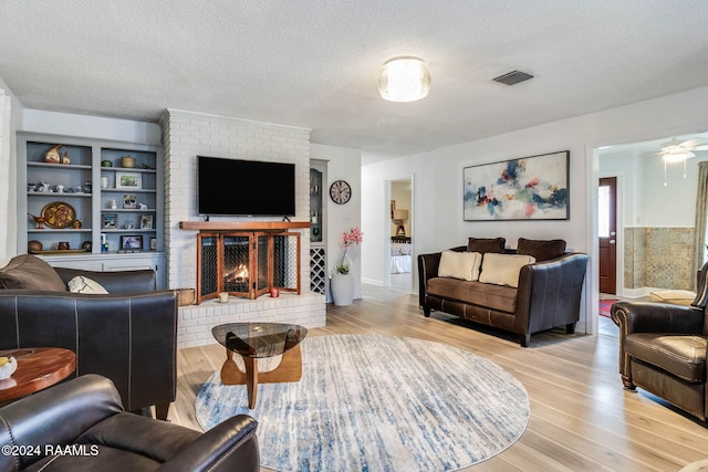 living room with a fireplace, a textured ceiling, hardwood / wood-style flooring, and ceiling fan