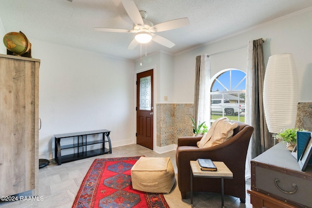 living area featuring ornamental molding, a textured ceiling, ceiling fan, and a healthy amount of sunlight