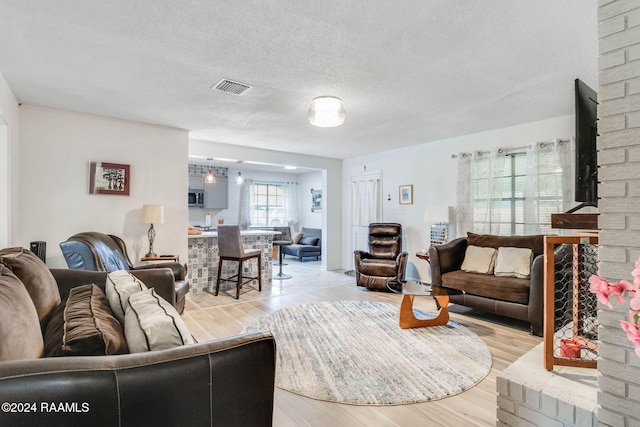 living room featuring light wood-type flooring and a textured ceiling