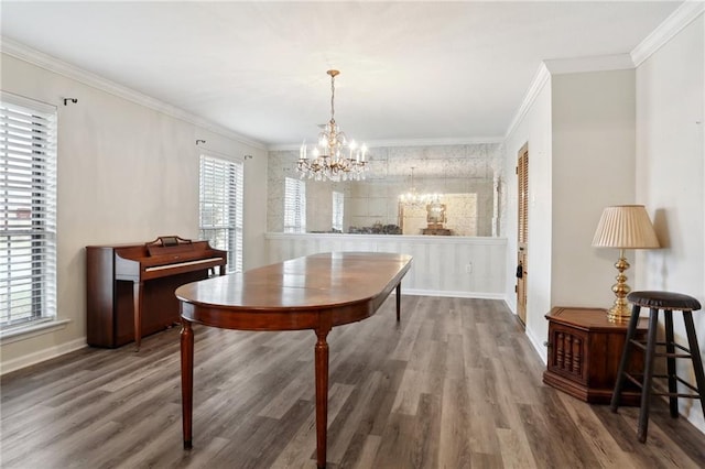 dining area featuring baseboards, ornamental molding, wood finished floors, and an inviting chandelier