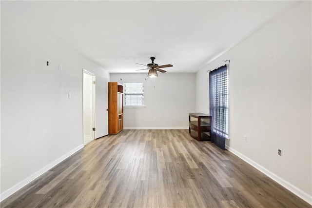 unfurnished room with a ceiling fan, baseboards, and wood finished floors