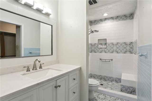 bathroom featuring visible vents, a tile shower, vanity, and toilet