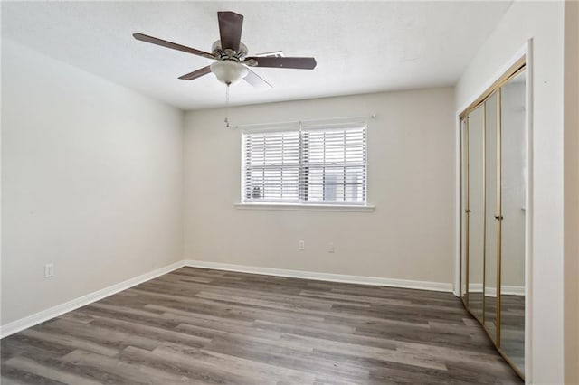 unfurnished bedroom with ceiling fan, a closet, wood finished floors, and baseboards