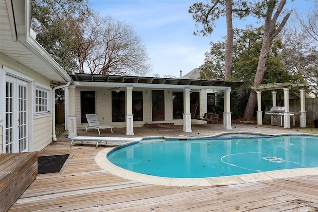 pool with ceiling fan, a deck, a diving board, and french doors