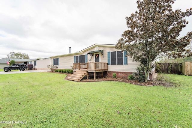 manufactured / mobile home featuring a front lawn and a wooden deck