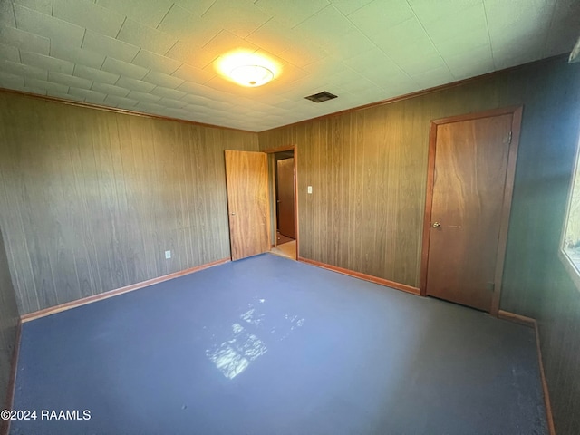 unfurnished bedroom with concrete flooring, a closet, and wood walls