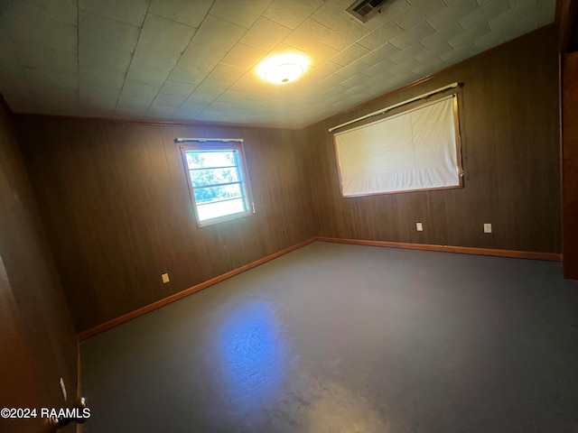 spare room with concrete flooring and wooden walls