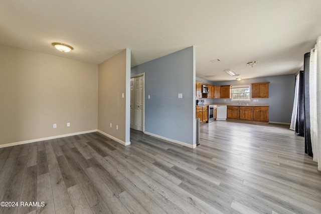 unfurnished living room with light hardwood / wood-style flooring and sink