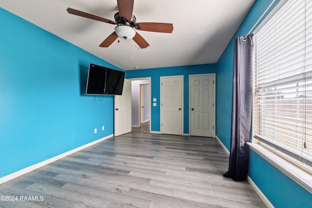 unfurnished bedroom with ceiling fan, light hardwood / wood-style floors, and vaulted ceiling