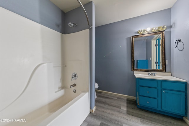 full bathroom featuring washtub / shower combination, vanity, hardwood / wood-style flooring, and toilet