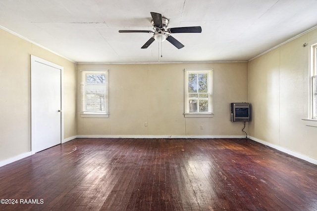 empty room featuring dark wood-type flooring, a wealth of natural light, and heating unit