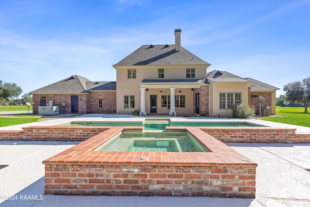 rear view of property with an in ground hot tub and ceiling fan