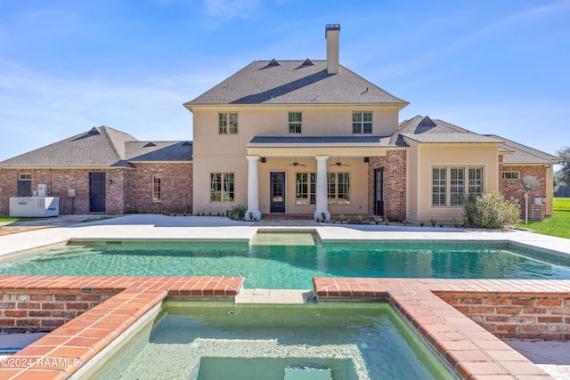 rear view of property featuring a patio area, ceiling fan, and a pool with hot tub