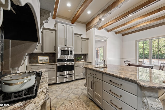 kitchen featuring appliances with stainless steel finishes, gray cabinets, a healthy amount of sunlight, and beam ceiling