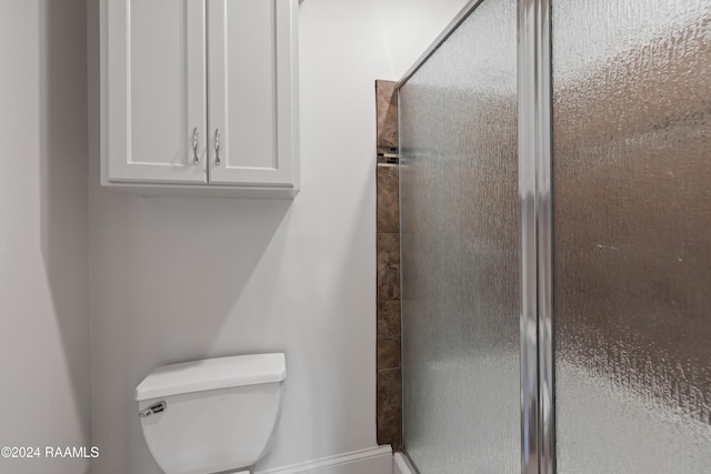 bathroom with toilet and a shower with shower door