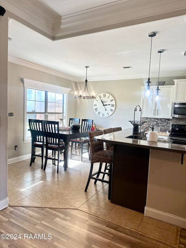 kitchen with crown molding, decorative light fixtures, light hardwood / wood-style flooring, white cabinets, and black range with electric stovetop