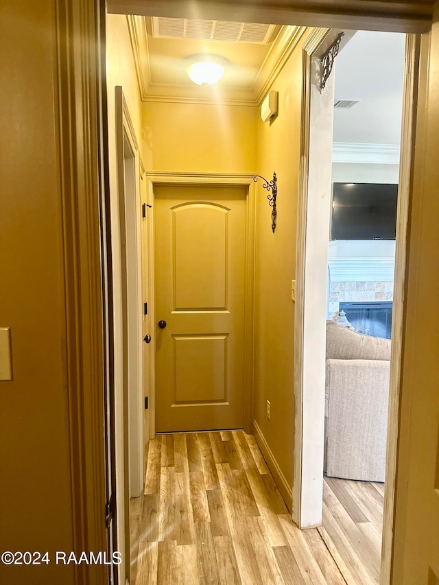 hallway with light hardwood / wood-style floors and ornamental molding