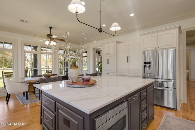 kitchen featuring white cabinets, light hardwood / wood-style flooring, appliances with stainless steel finishes, a kitchen island, and ornamental molding