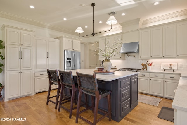 312 Shinnecock Hills Dr, Broussard, LA 70518 - kitchen with stainless steel fridge, wall chimney range hood, a center island, white cabinets, and crown molding