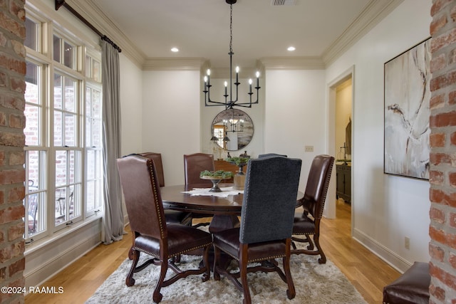 dining space featuring ornamental molding, light wood-type flooring, and a notable chandelier