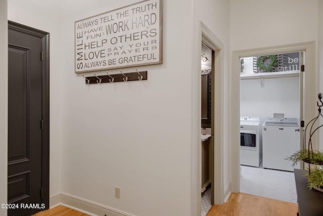 hall with washer and clothes dryer and light hardwood / wood-style flooring