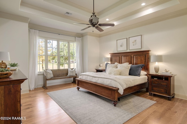 bedroom featuring light hardwood / wood-style floors, crown molding, ceiling fan, and a tray ceiling