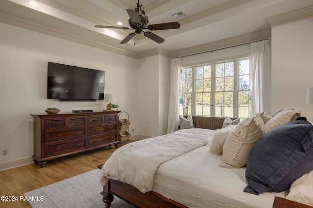 bedroom featuring a raised ceiling, crown molding, light hardwood / wood-style flooring, and ceiling fan