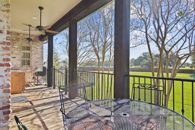 wooden terrace featuring ceiling fan and a yard