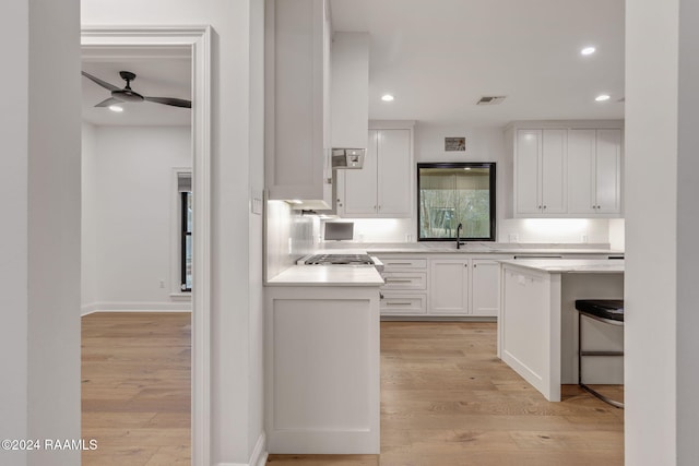 kitchen featuring light wood-type flooring, white cabinetry, ceiling fan, and sink