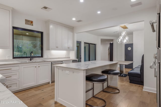 kitchen with a center island, stainless steel dishwasher, light wood-type flooring, and sink