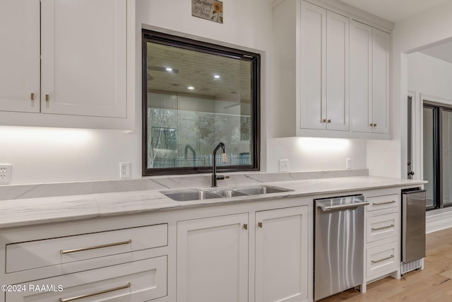 kitchen with light stone countertops, white cabinetry, sink, and light hardwood / wood-style flooring