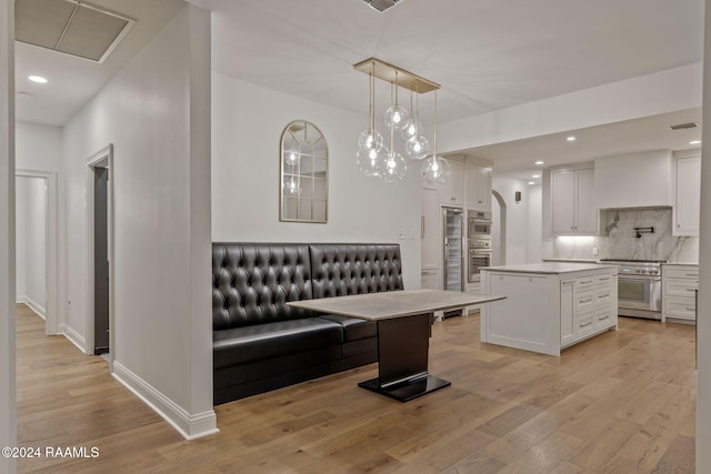 kitchen featuring custom exhaust hood, light hardwood / wood-style flooring, white cabinets, a center island, and stainless steel stove