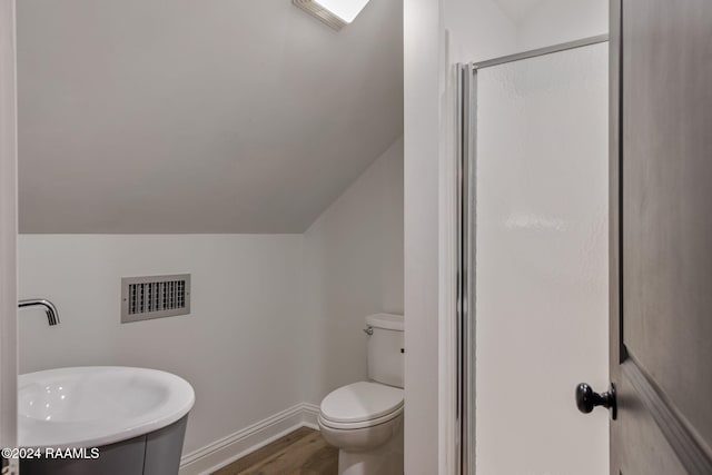 bathroom featuring toilet, vaulted ceiling, walk in shower, and sink