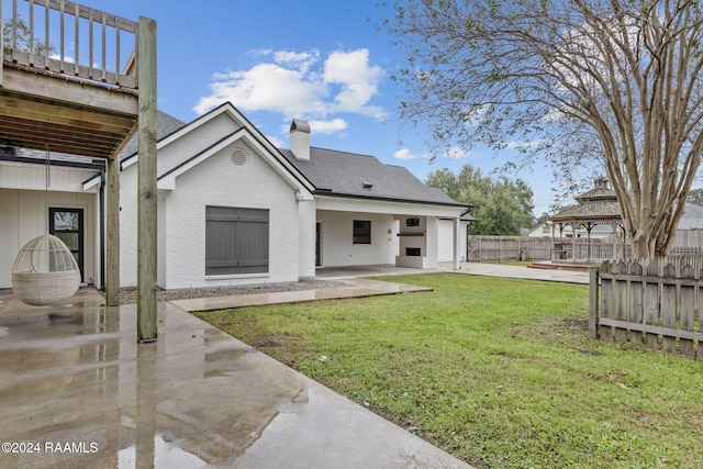 back of house with a lawn and a patio area