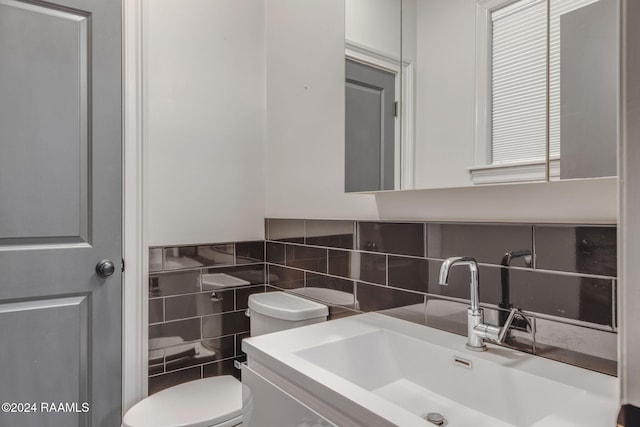 bathroom featuring vanity, toilet, tile walls, and backsplash